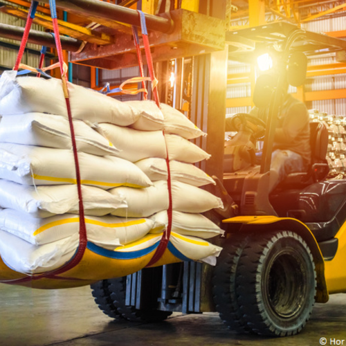 Ein Gabelstapler transportiert eine Ladung prallg gefüllter Säcke in einer großen Lagerhalle.