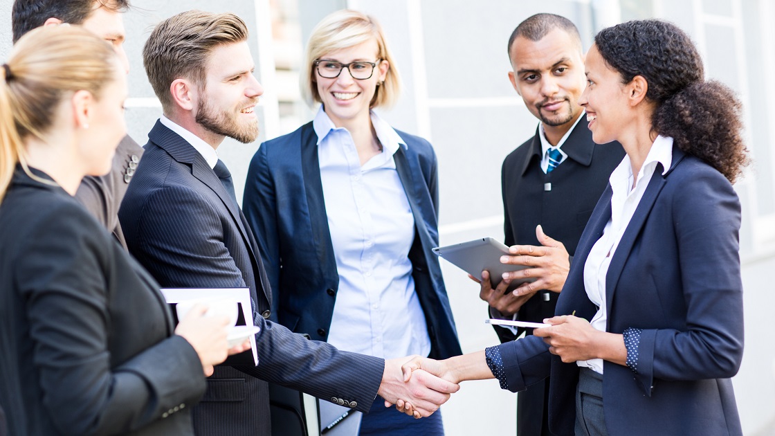 Eine Gruppe junger Geschäftspartnerinnen und Partner begrüßt sich per Handschlag.